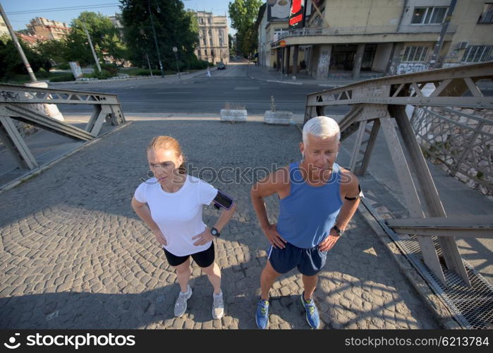 healthy mature couple jogging in the city at early morning with sunrise in background