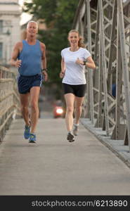 healthy mature couple jogging in the city at early morning with sunrise in background