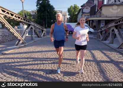 healthy mature couple jogging in the city at early morning with sunrise in background