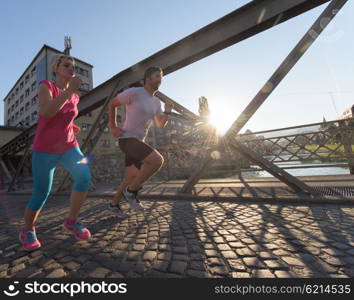 healthy mature couple jogging in the city at early morning with sunrise in background