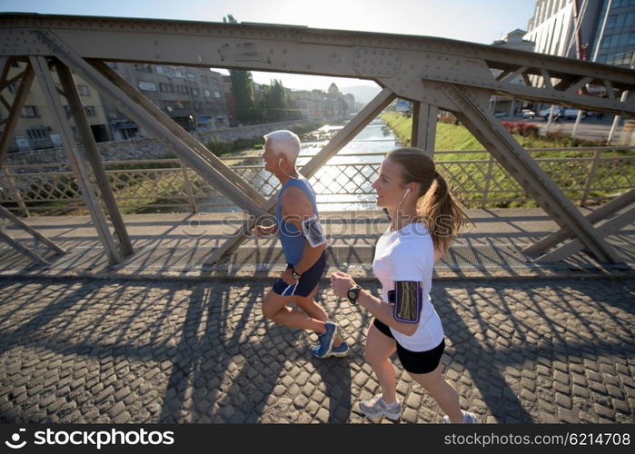 healthy mature couple jogging in the city at early morning with sunrise in background