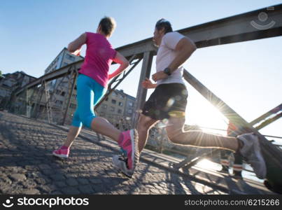 healthy mature couple jogging in the city at early morning with sunrise in background