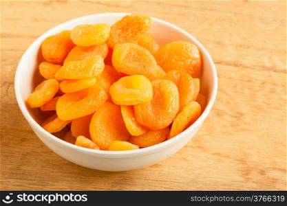 Healthy nutrition diet. Bowl of dried apricots on wooden table background.