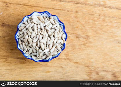 Healthy nutrition diet. Bowl of fresh sunflower seeds on wooden table background.