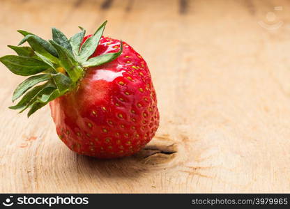 Healthy nutrition diet. Red fresh single strawberry fruit on wooden table board