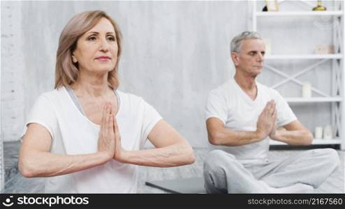 healthy old couple sitting lotus pose with praying hands