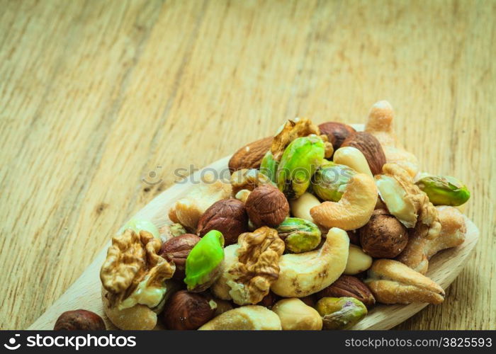 Healthy organic nutrition high fatty acids food and cuisine. Closeup varieties assortment mix of nuts on wooden spoon.