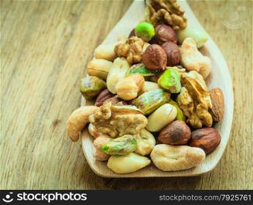Healthy organic nutrition high fatty acids food and cuisine. Closeup varieties assortment mix of nuts on wooden spoon.
