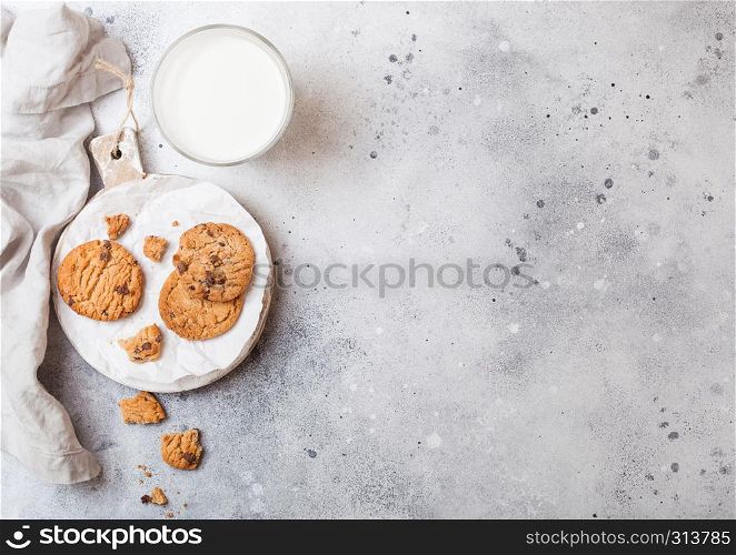 Healthy organic oat cookies with chocolate with glass of milk on wooden board on stone kitchen table background.