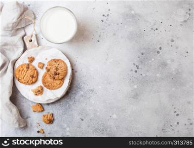 Healthy organic oat cookies with chocolate with glass of milk on wooden board on stone kitchen table background.