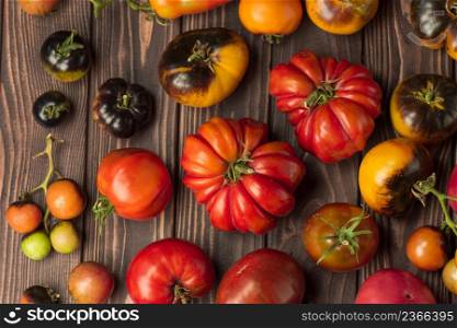 Healthy organic tomatoes on a wooden background. Assorted tomatoes on rustic wooden background. Red tomato on the table. Many tomatoes on wooden table. Fresh ripe organic garden tomatoes on wooden table.