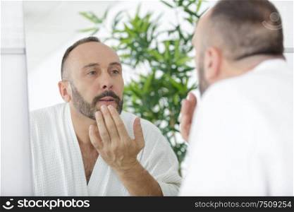 healthy positive male treating skin with lotion after shaving