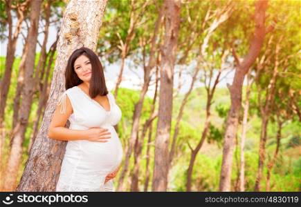 Healthy pregnant woman in the garden in warm sunny day, enjoying pregnancy, relaxation outdoors, happy motherhood, new life concept
