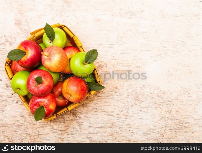 Healthy red and green apples in vintage basket on wood background.