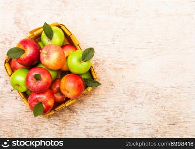 Healthy red and green apples in vintage basket on wood background.