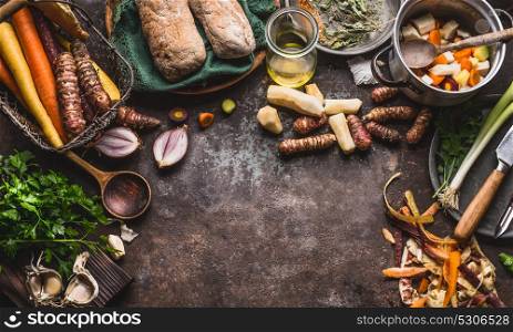 Healthy root vegetables cooking and eating concept. Various vegetables with knife and pot on dark kitchen table background , top view. Vegetarian dishes cooking