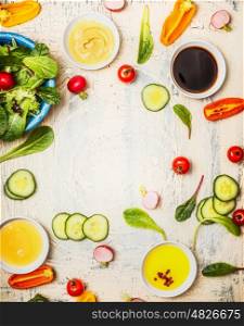 Healthy salad preparation with various dressings ,cutlery and vegetables on white rustic background, top view, frame. Diet eating, Vegetarian or vegan food concept