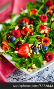 Healthy salad with arugula,spinach,smoked salmon and berries