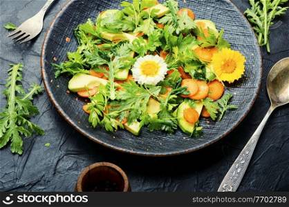 Healthy salad with chrysanthemum and avocado leaves,carrots and green.Fresh summer green salad with edible flowers. Diet salad with chrysanthemum leaves and avocado