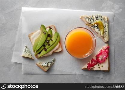 Healthy sandwich with fresh vegetables and orange juice on a gray stone background. fresh sandwiches with juice