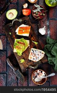 healthy sandwiches with smoked salmon avocado cucumber cream cheese on rye bread on dark background