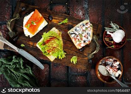 healthy sandwiches with smoked salmon avocado cucumber cream cheese on rye bread on dark background