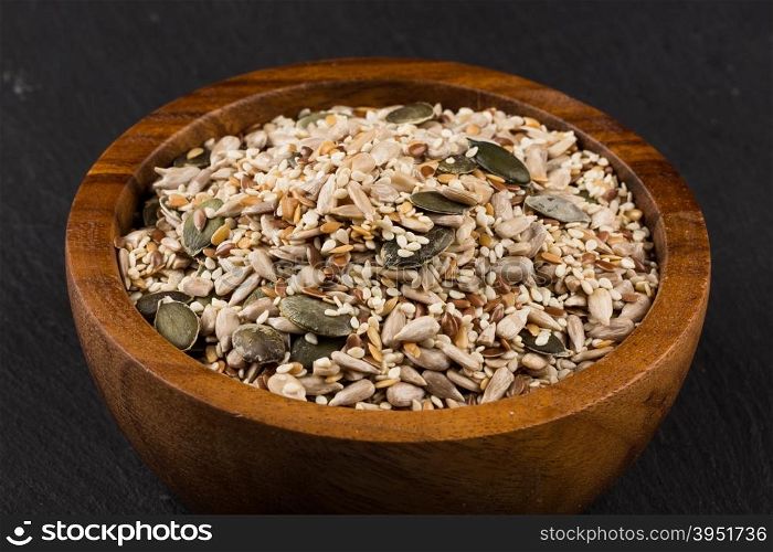 Healthy seeds mix in a wooden bowl on stone background