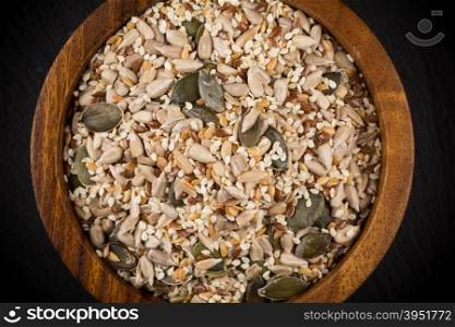 Healthy seeds mix in a wooden bowl on stone background