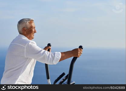 healthy senior man working out on gym treadmill machine at modern home terace with ocean view