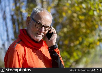 Healthy senior runner man on the phone outdoor park