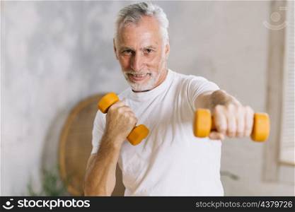 healthy smiling senior man working out with dumbbells