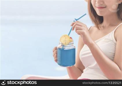 Healthy soft drink good health lifestyle with young happy woman drinking blue Hawaii fresh ingredients organic juice. Beautiful woman holding glass with smiling face healthy diet drinking water.