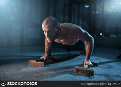 Healthy sportsman makes pushups exercises on training. Strong gymnast on workuot. Sportsman makes pushups exercises on training