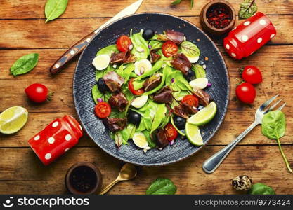 Healthy spring salad with greens, tomato, egg, lime slices of meat on wooden table. Spring salad with meat.