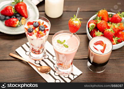 Healthy strawberry smoothie in glass on rustic wood