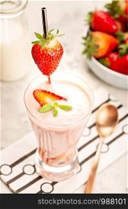 Healthy strawberry smoothie in glass on white marble