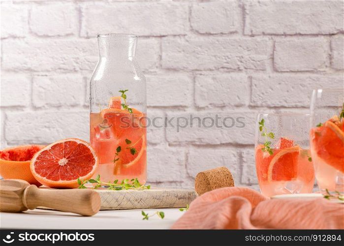 Healthy summer drink grapefruit lemonade with thyme in glasses with ice on a wooden surface.