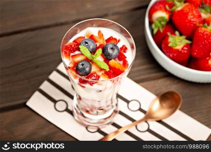 Healthy sweet dessert in glass with strawberries, yogurt and blueberries. Healthy food concept