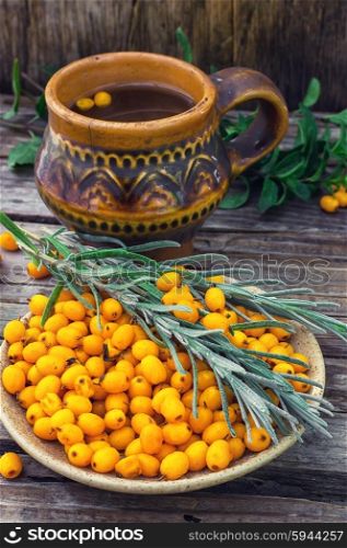 Healthy tea with sea buckthorn.. Still life with tea with fresh sea-buckthorn berries in rustic style.