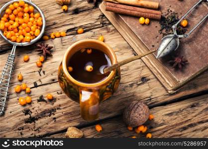 healthy tea with sea-buckthorn. teacup with healing berry tea with sea-buckthorn on retro background
