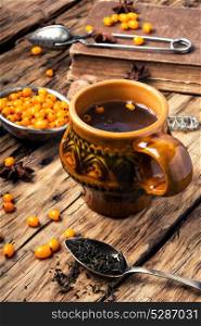 healthy tea with sea-buckthorn. teacup with healing berry tea with sea-buckthorn on retro background
