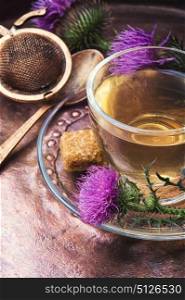 healthy tea with thistle. glass cup on saucer with tea from a medicinal inflorescence thistle