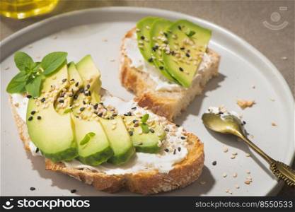 Healthy toast with avocado cream cheese and wheat bread on a plate. Delicious snacks and avocado sandwiches. Food composition, tasty Italian meal.
