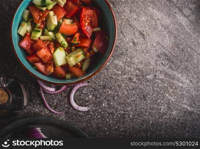 Healthy tomatoes cucumber salad served on gray stone background, top view, close up. Healthy, diet and clean food and eating concept.