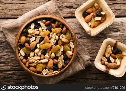 Healthy trail mix snack made of nuts (walnut, almond, peanut) and dried fruits (raisin, sultana) in wooden bowl, photographed overhead (Selective Focus, Focus on the trail mix in the big bowl). Trail Mix Snack of Nuts and Dried Fruits