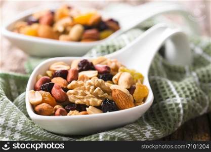 Healthy trail mix snack made of nuts (walnut, almond, peanut) and dried fruits (raisin, sultana) on spoons (Selective Focus, Focus one third into the first spoon). Trail Mix Snack of Nuts and Dried Fruits