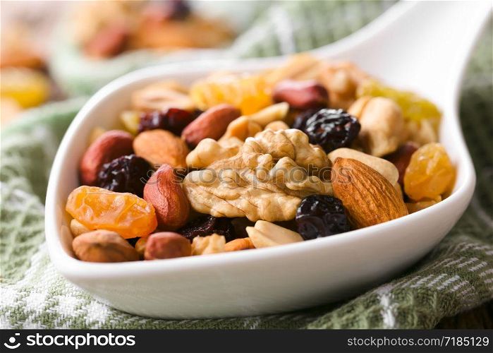 Healthy trail mix snack made of nuts (walnut, almond, peanut) and dried fruits (raisin, sultana) on spoon (Selective Focus, Focus one third into the spoon). Trail Mix Snack of Nuts and Dried Fruits