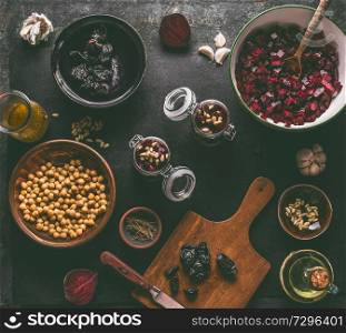 Healthy vegan beetroot salad preparation with ingredients: chickpeas and pine nuts on dark kitchen table background , top view. Purple vegetables eating. Clean dieting food.