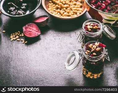 Healthy vegan beetroot salad with chickpeas and pine nuts in glasses for lunch on dark kitchen table background with ingredients, top view. Purple vegetables eating. Clean dieting food.