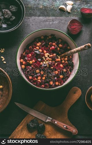 Healthy vegan beetroot salad with chickpeas in bowl on dark kitchen table background, top view. Purple vegetables eating. Clean dieting food.